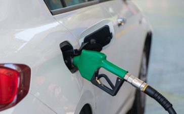 Surtidor de gasolina con boquilla verde repostando combustible a un vehículo.