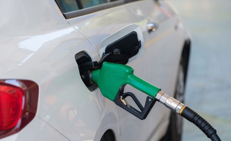 Surtidor de gasolina con boquilla verde repostando combustible a un vehículo.